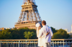 A couple enjoying a romantic stay in Paris for Valentine's Day, they embrace in front of the Eiffel Tower.